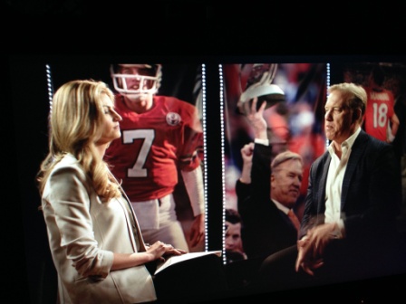 John Elway speaking during a filmed interview with a host on a production set